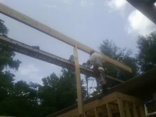 Carpenter setting a ridge beam over a new addition frame — Ice Dam Removal by Roofing Brothers in Green Isle