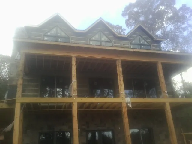 Dormers and porch framing on a large log home under construction — Roof Coating work by our crew in Green Isle