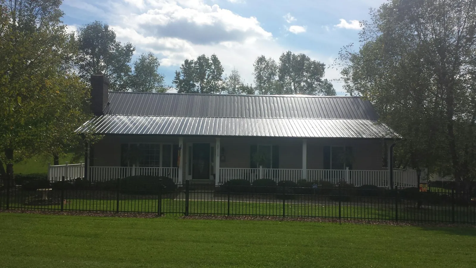 Gray metal roof on a brick ranch with a full width front porch — Gutter Guard Installation work by our crew in Green Isle