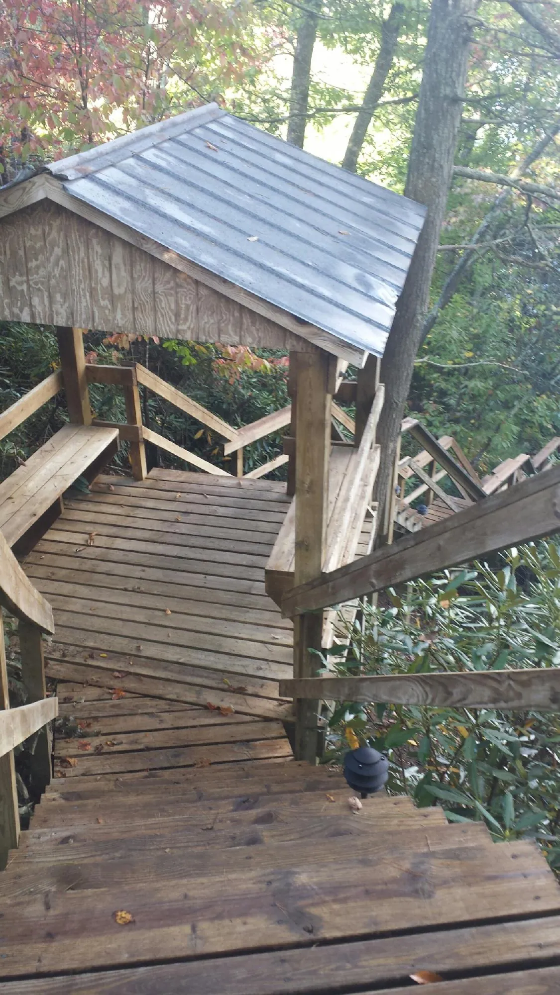 Metal roofed shelter over wooden steps on a wooded walkway — Skylight Repair & Installation work by our crew in Green Isle