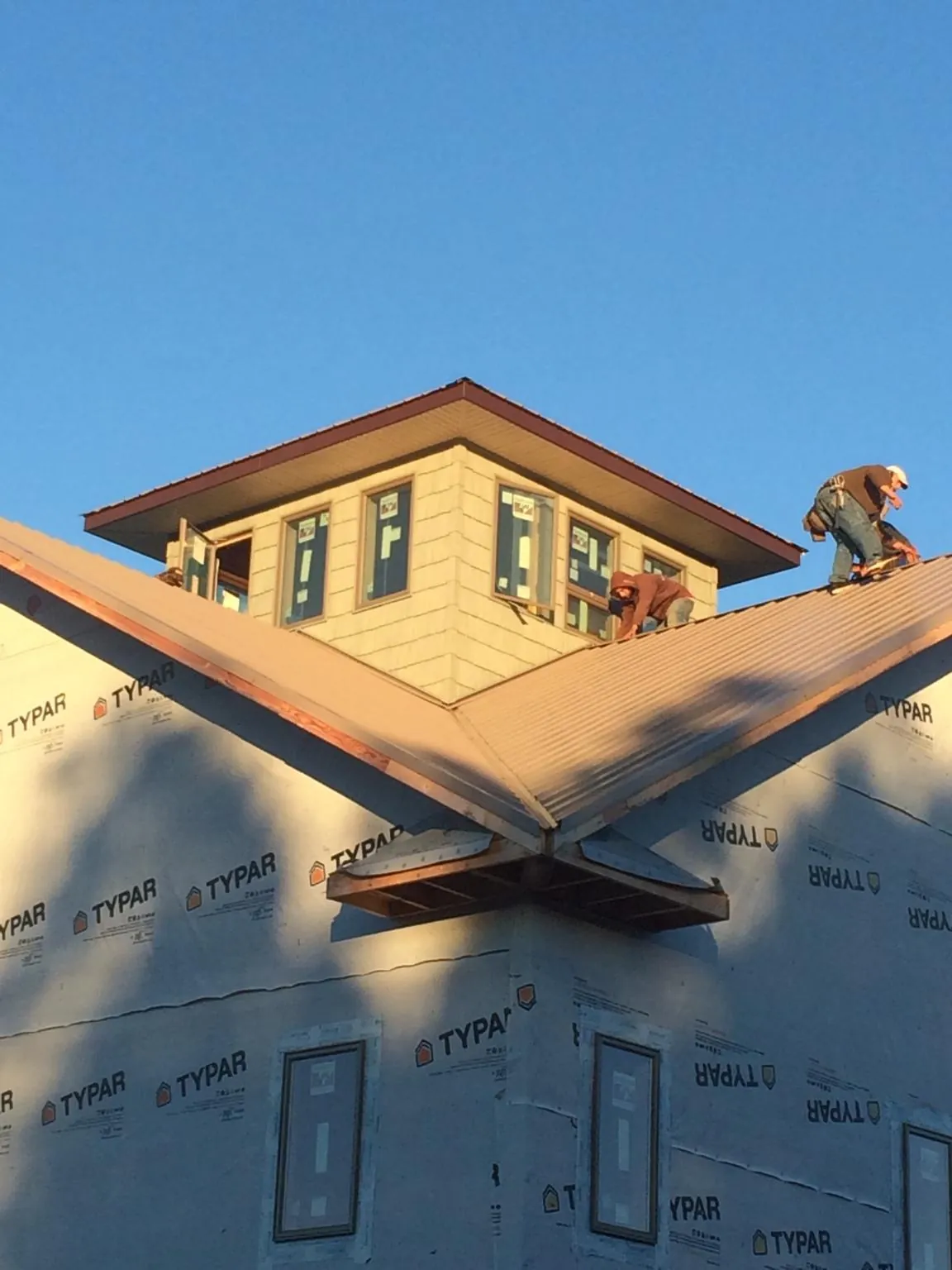 Roofers working around a rooftop cupola on a new metal roof at sunset — Roof Waterproofing in Green Isle by Roofing Brothers